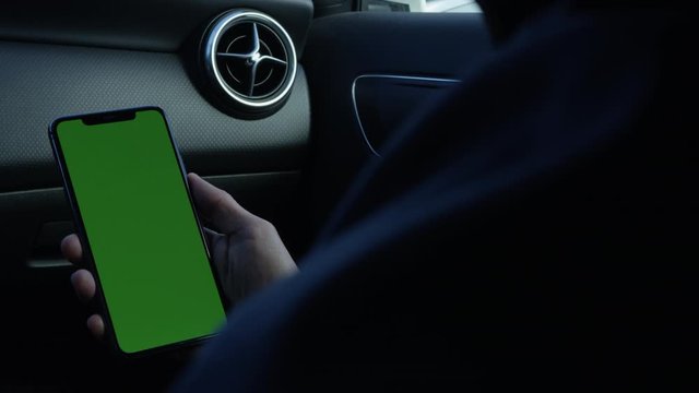 Using smartphone inside the car tapping and swiping holding phone with green screen