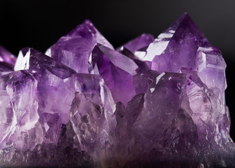 Raw violet amethyst rock with crystals on the black background