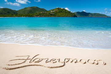 Romantic island honeymoon message written in smooth sand on bright tropical beach