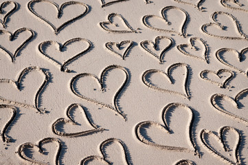 Romantic background of handwritten hearts drawn in smooth sand on a sunny beach