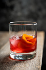 Red traditional old fashioned cocktail with orange zest on the rustic background. Selective focus. Shallow depth of field.
