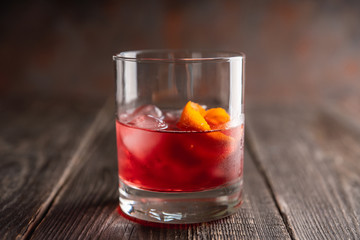 Red traditional old fashioned cocktail with orange zest on the rustic background. Selective focus. Shallow depth of field.