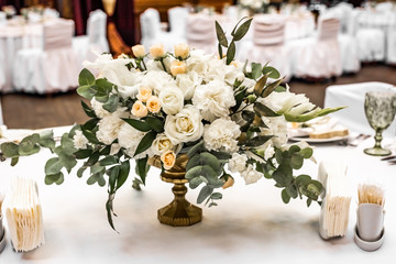 The bride's bouquet of white and yellow flowers on wedding arrangement in restaurant. Beautiful bridal bouquet of white and yellow peonies and roses on the table in the restaurant