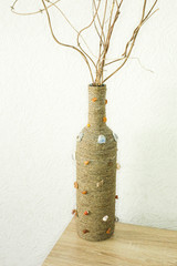 Handmade rustic vase made from bottle of vine with dry branches. Home design element.Vertical photo.