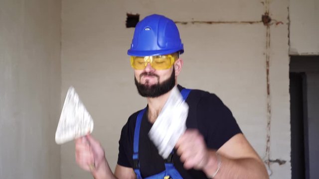 Cheerful male builder plasterer dancing at a construction site