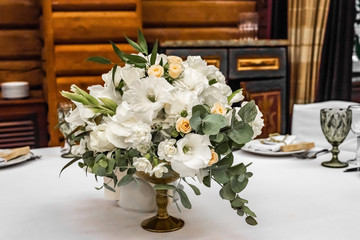 The bride's bouquet of white and yellow flowers on wedding arrangement in restaurant. Beautiful bridal bouquet of white and yellow peonies and roses on the table in the restaurant