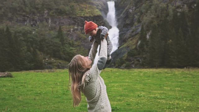 Mother holding up baby family vacation travel outdoor happy emotions woman with child together healthy lifestyle  trip in Norway waterfall and forest landscape