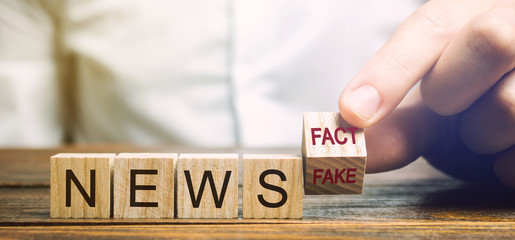 A man puts wooden blocks with the words News - Fact or fake. False / true information concept....