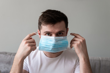 Scared Man in medical mask looks in camera. Scared man in fear of coronavirus stands in protective medical mask against viruses and infections isolated studio. Coronavirus 2019-ncov covid-19 concept.