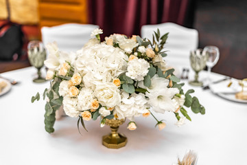 The bride's bouquet of white and yellow flowers on wedding arrangement in restaurant. Beautiful bridal bouquet of white and yellow peonies and roses on the table in the restaurant