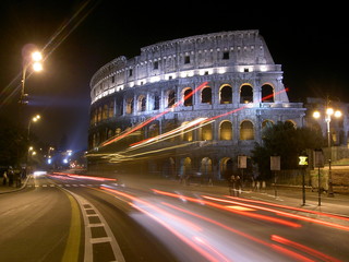 El Coliseo de Roma de noche mientras el tr&aacute;fico deja luces arrastradas por delante del edificio