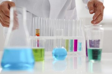 Male chemist holds test tube of glass in his hand overflows a liquid solution of potassium...