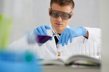 Male chemist holds test tube of glass in his hand overflows a liquid solution of potassium...