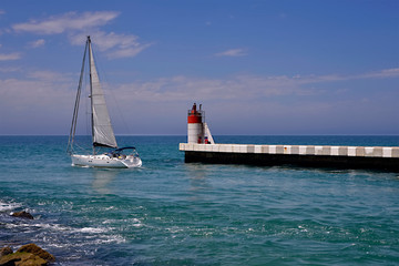 Lighthouse of Capbreton with a sailboat leaving the port. Capbreton is a commune in the Landes...