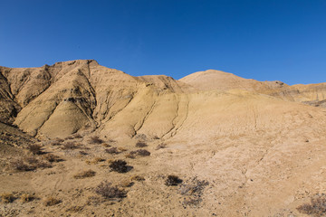 yellow sand hills in nature reserve in south coast of Issyk Kul with deep blue sky in Kyrgyzstan