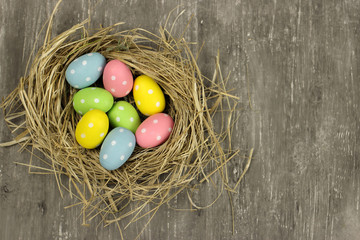 Colored Easter eggs in a nest on a gray background, top view