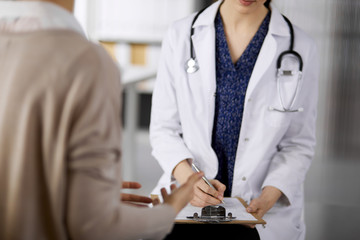 Doctor and patient discussing current health examination while sitting in clinic. Perfect medical...