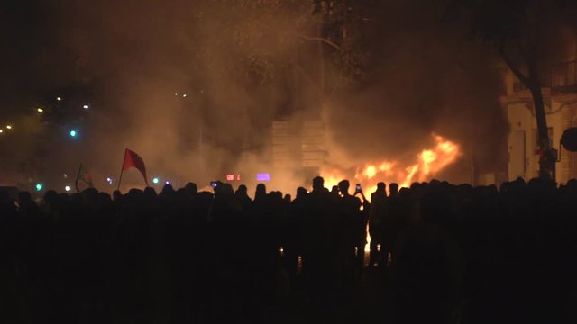Crowds of revolutionary people involved in street riots with barricades and burning dumpsters in front of the police