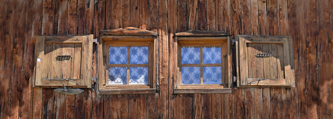 close on  two little windows on a wooden facade of old alpine chalet