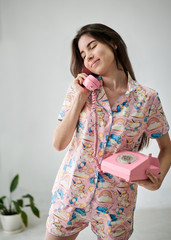 Young pretty slim brunette woman, wearing colorful pink pajamas with unicorn pattern, posing for...