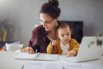 Young businesswoman working from home. Young mother working on lap top  at her home office. She...