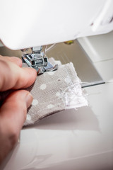 Woman's hands sewing on a white sewing machine.