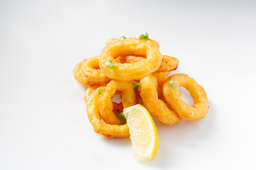Fried onion rings on white background with lemon