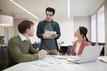 Group of financial advisors sitting at the table and listening to their manager during a meeting at office