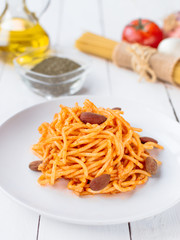 White plate with spaghetti on a white wooden table.