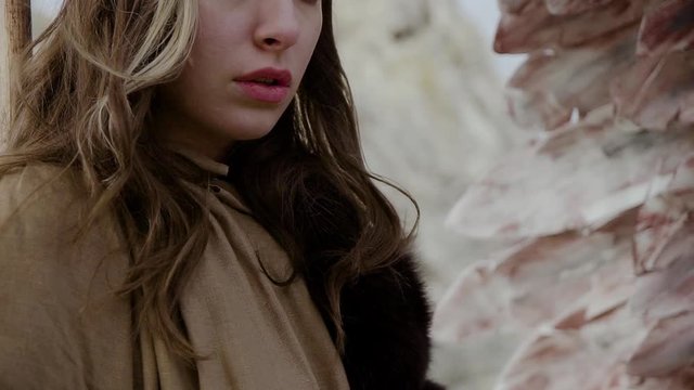 Young beautiful woman model with brown skin, brown eyes with brown hair, depicts sadness and looks anxiously at the camera against the background of bird wings