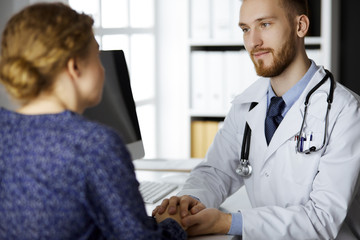 Obraz premium Friendly red-bearded doctor reassuring his female patient. Medical ethics and trust concept, medicine theme
