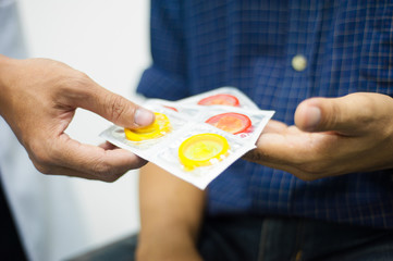 Close up the doctor advised the young man to prevent venereal disease using a condom.
