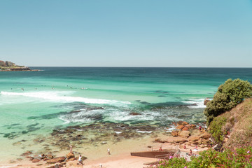 Bondi Beach Sydney holiday scene. Famous vacation spot in city, with beautiful ocean, sun, sea and sand. Tourists sunbathing on beach, with waves washing in. Australia.