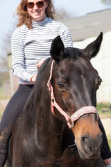 Obraz premium Portrait of a horse, brown horse head, a young girl is sitting on her back, focus on horse