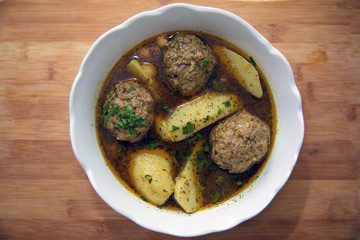 Traditional Azerbaijani Kufta bozbash - pea soup with lamb meatballs, made of minced meat and rice, zesty dried plum inside and boiled potatoes topped with dried mint and sumac . Kufta bozbash soup .