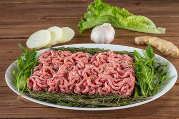 minced meat with greens and spices in a plate on a wooden table