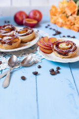 gebackene Blätterteigrosen mit Pflaumen und Puderzucker auf  hellen blauen Brettern aus Holz im nostalgischen Stil wie früher bei Oma