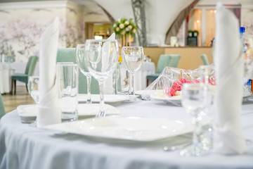 The table in the restaurant is served for dinner. On a table with a white tablecloth, empty wine glasses, a plates, napkins. Selective focus