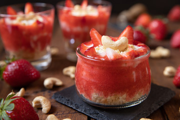 Püree mit Erdbeeren und Cashewjoghurt gehackt und gestückelt als süße Nachspeise auf dunklen...