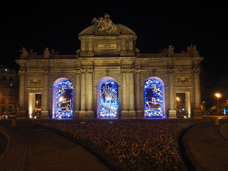 Fototapeta premium Puerta de Alcalá, monumento en el centro de Madrid, iluminado por la noche con luces de Navidad.
