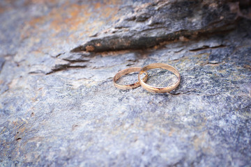 two wedding rings lie on the grey stone