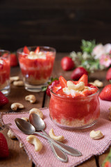 P&uuml;ree mit Erdbeeren und Cashewjoghurt gehackt und gest&uuml;ckelt als s&uuml;&szlig;e Nachspeise auf dunklen Brettern aus Holz in einem rustikalen Stil