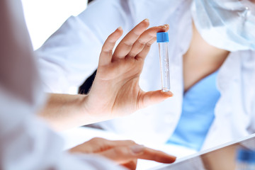 Coronavirus pandemic. Professional female scientist in protective eyeglasses researching tube with...