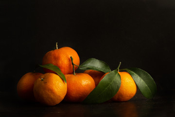 Mandarinas con hojas sobre un fondo negro. Vista de frente y de cerca. Copy space