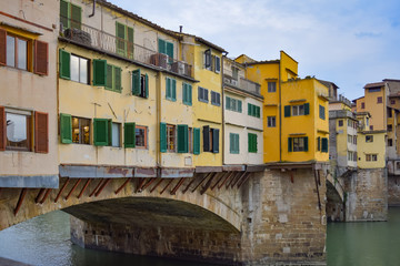 Fototapeta na wymiar A close up of the colorful yellow and green shops that line the Ponte Vecchio that crosses the Arno River in Florence, Italy.