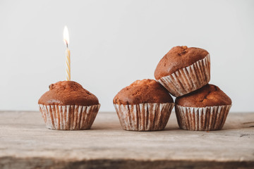 Chocolate cupcakes with candle on wooden table. Copy, empty space for text
