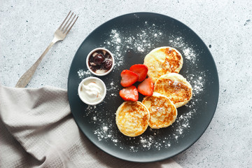 Tasty cheese pancakes with strawberries, sour cream and cherry jam. Cheese pancakes on a plate