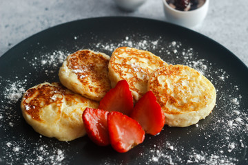 Tasty cheese pancakes with strawberries, sour cream and cherry jam. Cheese pancakes on a plate