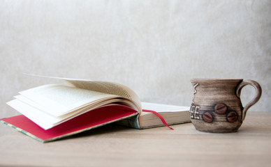 Сup of coffee with books on the table. 
Books and cup of coffee or tea on a wooden table. 
Cup of...