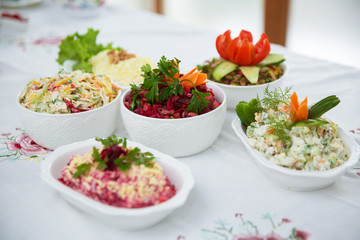 Diet salad with beets . Capital salad . Potato salad . coleslaw salad . set with different salads . Salad ham, orange pepper, mushrooms, pickles, white sauce, on a white bowl.